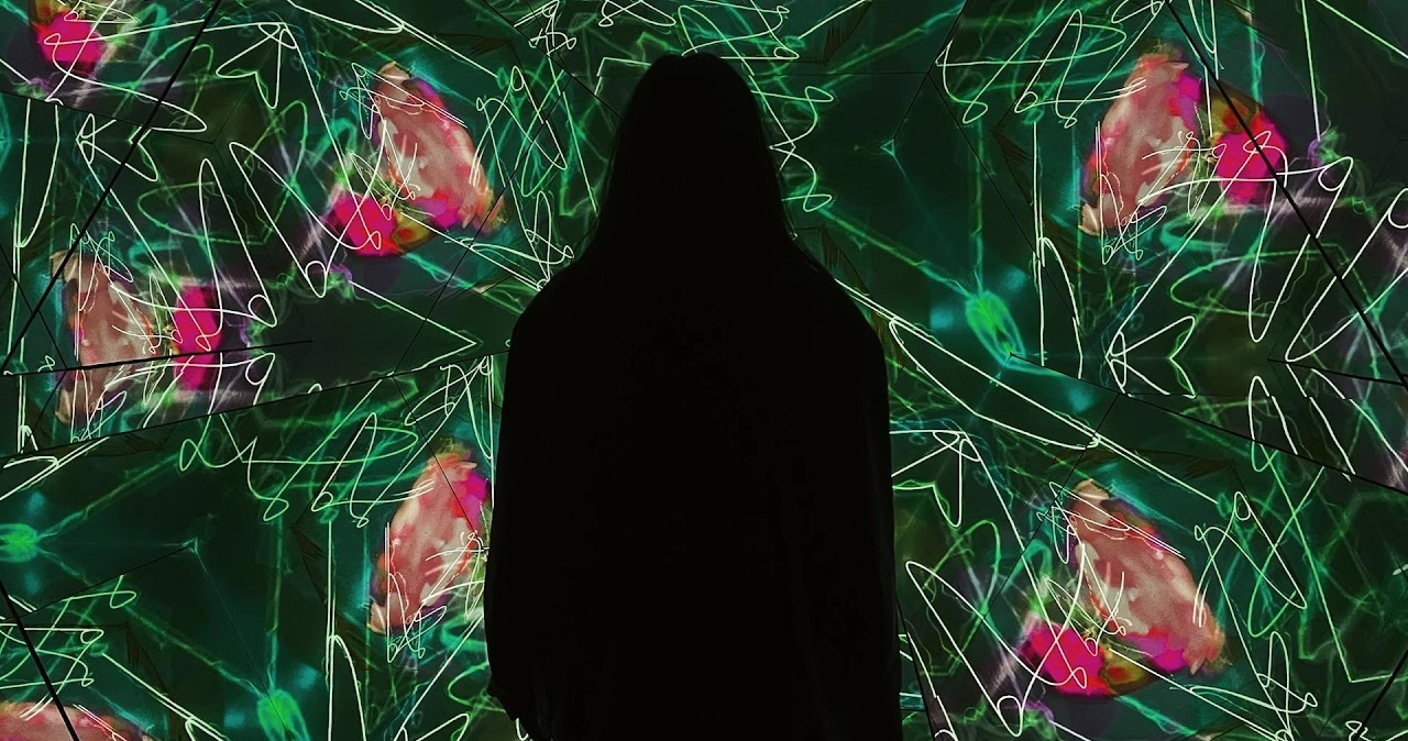Visitor experiencing green and pink abstract interactive installation in Holoseum kaleidoscope room