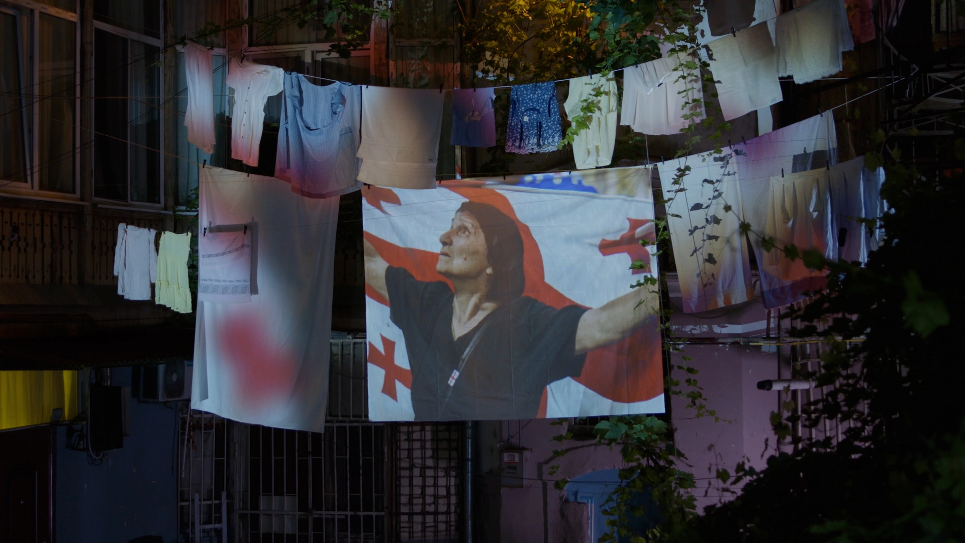 Digital projection of woman with Georgian flag on hanging laundry in outdoor courtyard
